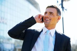 Portrait of a smiling businessman talking on the phone at street